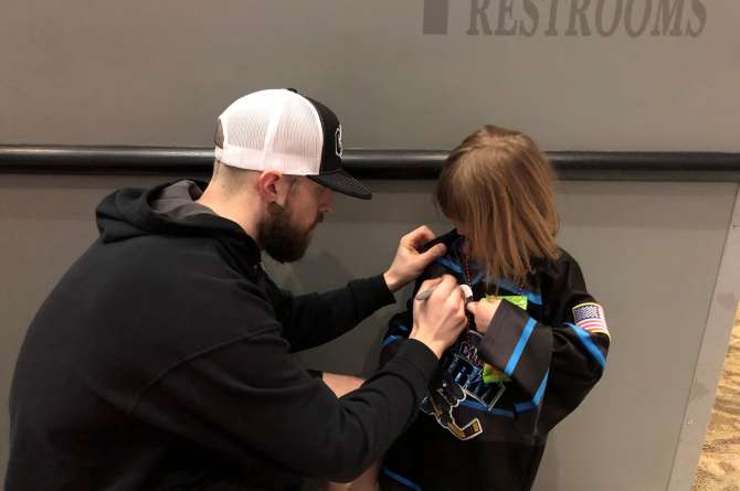 A hockey player signing a kid's jersey