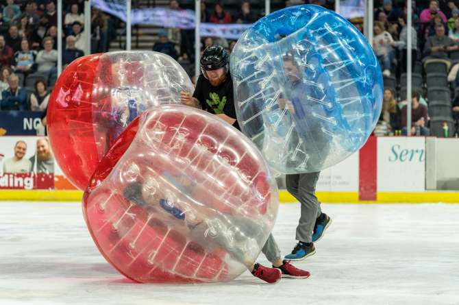 People on the ice in blow up bouncing balls
